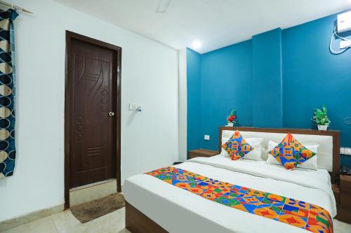 1 dormitorio con 1 cama con pared azul en FabHotel Usha Continental, en Muthiganj