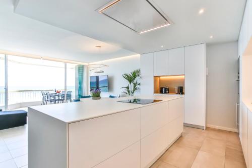 an open kitchen with white cabinets and a dining room at MAGNÍFICO APARTAMENTO - primera línea de mar in Calafell