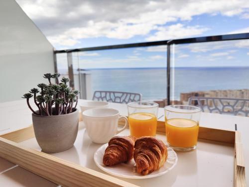 stół z dwoma filiżankami soku pomarańczowego i rogalikami w obiekcie SUNSET WAVES DReaM apartment w mieście Benidorm