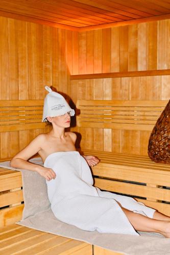 a woman is sitting in a sauna at Hotel Sokół Wellness & SPA in Łańcut