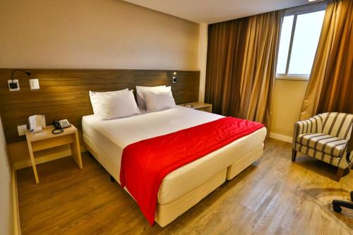 a hotel room with a large bed and a chair at Ibiza Plaza Hotel in Anápolis