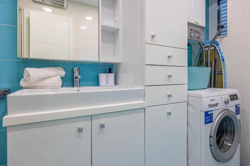 a white bathroom with a sink and a washing machine at Villa Veronika Apartments in Crikvenica