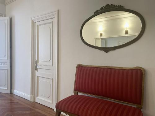 uma cadeira vermelha num quarto com um espelho em Apartamentos Alcalá em Madri