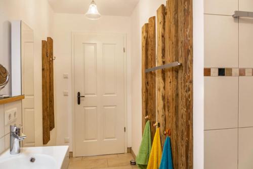 a bathroom with a white sink and a wooden door at Lina in Rottenbuch