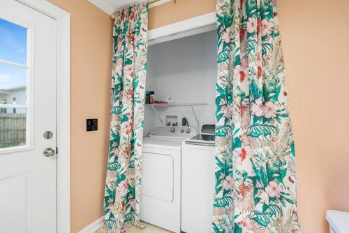 a kitchen with a window with a floral curtain at Crescent Beach Bungalow B in Saint Augustine