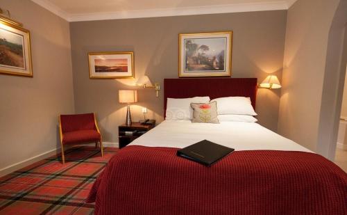 Habitación de hotel con cama con manta roja en Kirkhouse Inn, en Milngavie