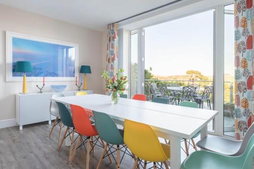 a dining room with a white table and colorful chairs at Old Sail Loft in Salcombe
