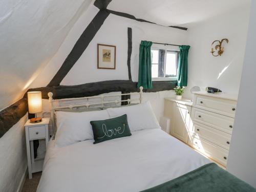 a bedroom with a white bed with a green pillow at Bluebell Cottage in Stratford-upon-Avon