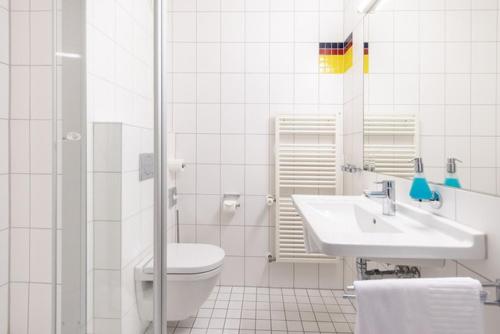 La salle de bains blanche est pourvue de toilettes et d'un lavabo. dans l'établissement Hotel ISG Heidelberg, à Heidelberg