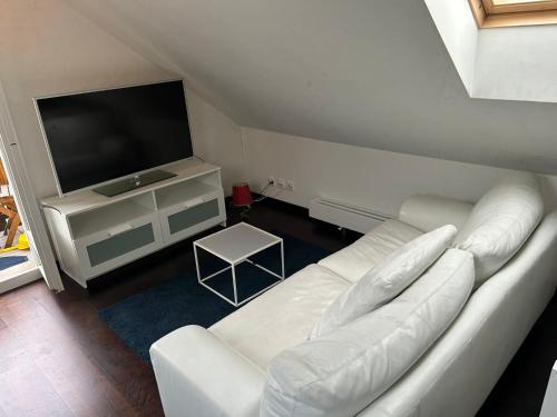 a living room with a white couch and a flat screen tv at M-Hostel in Lucerne