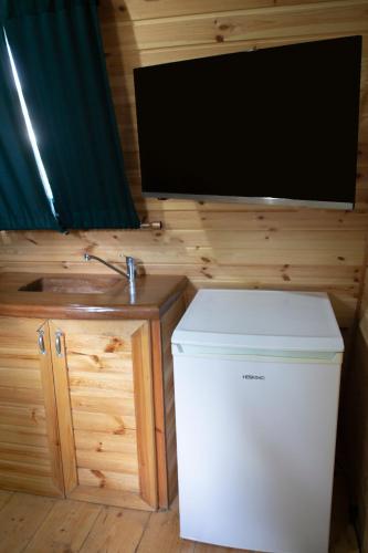 a small white refrigerator and a tv on a wall at Captain Ikaros in Agios Kirykos