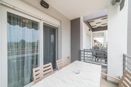 a dining room with a table and a balcony at Nefeli & Nefeli Luxury Residential Complexes in Ofrínion