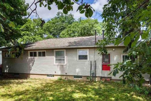 a white house with a red door on a yard at {Hot Tub in Ranch} Mins to Airport/UofR/Strng/Dwtn in Rochester