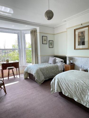 a bedroom with two beds and a desk and a window at The Raffles in Exeter