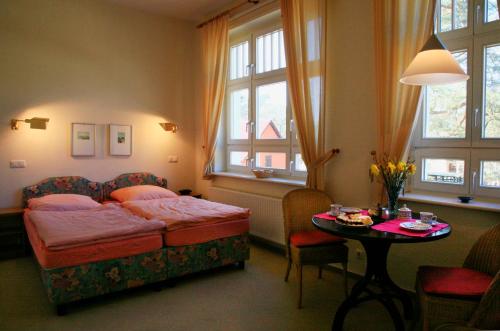 Schlafzimmer mit einem Bett, einem Tisch und Fenstern in der Unterkunft Villa Daheim - FeWo 03 in Ostseebad Kölpinsee