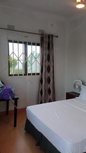 1 dormitorio con cama blanca y ventana en SUITE HUTAMI en Vila Praia Do Bilene