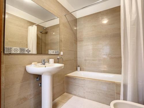 un baño con lavabo y bañera en Amarelo Apartment by Atlantic Holiday, en São Vicente