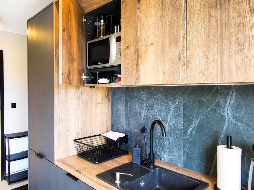 a kitchen with a sink and a microwave at Sowie Chatki - domki z widokiem na Góry Sowie in Sokolec