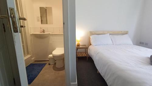 a bedroom with a bed and a bathroom with a toilet at Bright & Chilled DB room with own bathroom! in London
