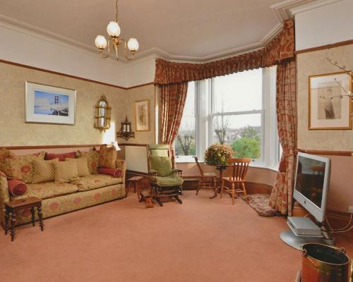 uma sala de estar com um sofá e uma televisão em The Raffles em Exeter