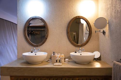 a bathroom with two sinks and two mirrors at Nyati Safari Lodge in Hoedspruit