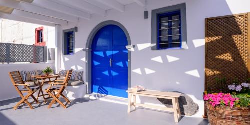 a blue door on a white building with a table and chairs at Casa Delle Botti Cave House Santorini Oia Finikia in Foinikiá