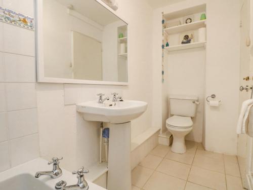 a white bathroom with a sink and a toilet at Blue Reef Cottage in Lower Boscaswell