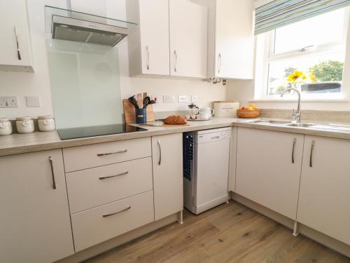 a kitchen with white cabinets and a sink at Pebble Bay in Bideford