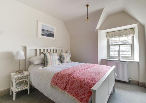 a bedroom with a bed with a red blanket and a window at Wyvern Cottage in Swanage