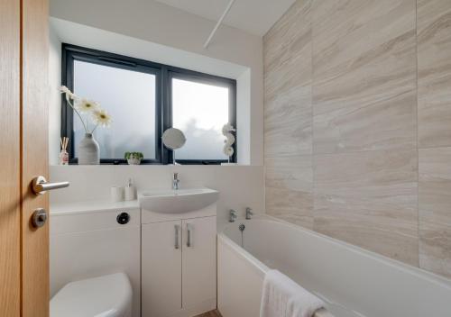 een badkamer met een wit bad, een wastafel en een bad tubermott bij SeaBreeze Holiday Apartment in Swanage