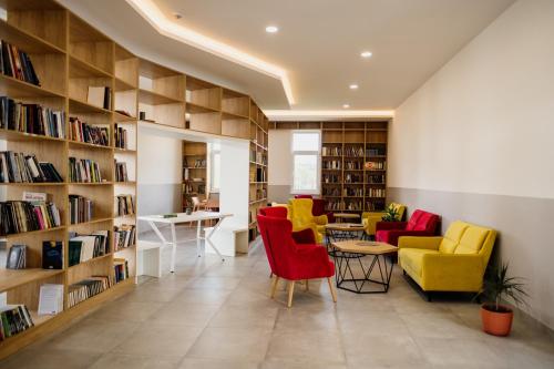 eine Bibliothek mit gelben und roten Stühlen und Bücherregalen in der Unterkunft CIOM Apartment in Matuzići