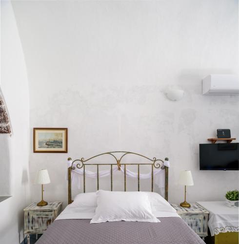 a bedroom with a bed and two tables with lamps at Casa Delle Botti Cave House Santorini Oia Finikia in Foinikiá