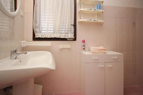 een witte badkamer met een wastafel en een spiegel bij Apartman Nada in Punat