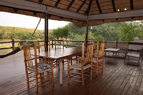 a wooden table and chairs on a deck at Nyati Safari Lodge in Hoedspruit