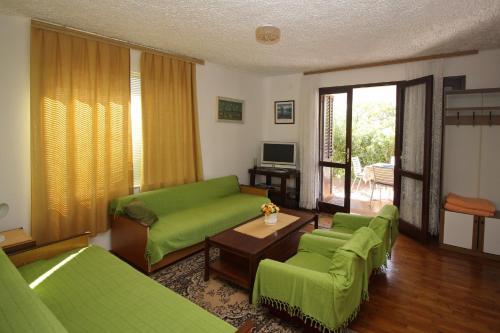- un salon avec des canapés verts et une table dans l'établissement Apartman Nada, à Punat