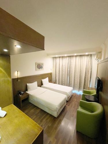 a bedroom with a white bed and a green chair at Royal Garden Hotel in Beirut