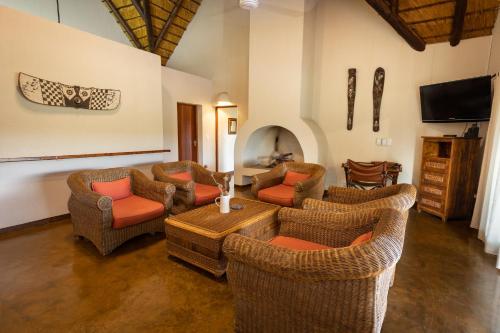 a living room with couches and chairs and a television at Nyati Safari Lodge in Hoedspruit