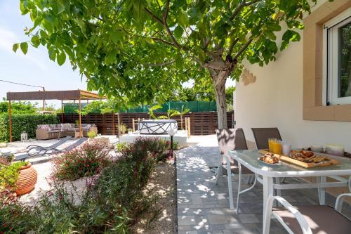 a patio with a table and chairs under a tree at Mikros Paradeisos in Theologos