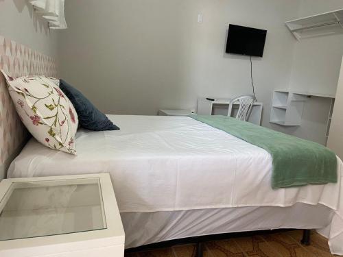 a bedroom with a large white bed with a table at Studio Universitário in Jacobina