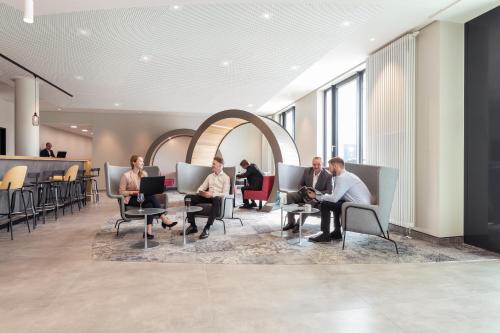 デュッセルドルフにあるNovotel Duesseldorf Airportのロビーの椅子に座る人々