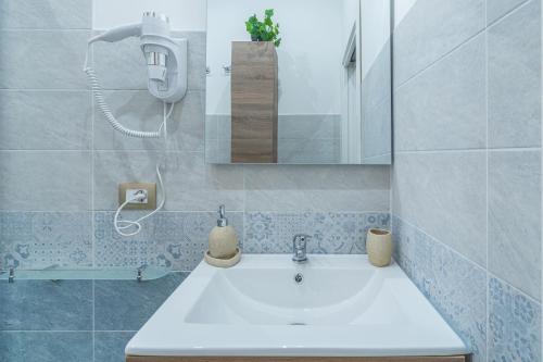 ein Badezimmer mit einem weißen Waschbecken und einem Spiegel in der Unterkunft Dimora D&G in Syrakus