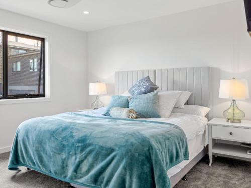 a white bedroom with a bed with a blue blanket at Luxury 5 Bedroom Home - Sentinel Chalet - Snowy Mountains - Jindabyne in Jindabyne