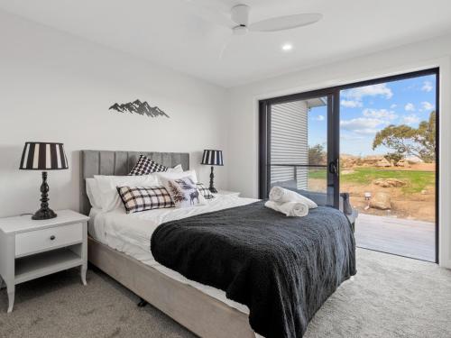 a bedroom with a bed and a large window at Luxury 5 Bedroom Home - Sentinel Chalet - Snowy Mountains - Jindabyne in Jindabyne