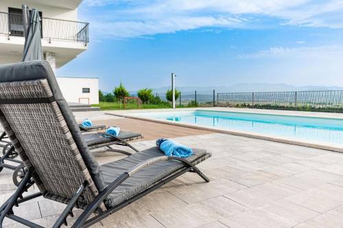 un par de sillas sentadas junto a una piscina en Luxury Villa Rilassante-Heated Pool,Full Privacy,Children Playground, en Sinj