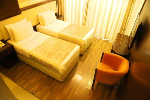 a hotel room with two beds and a chair at Royal Garden Hotel in Beirut