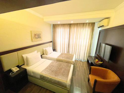 a hotel room with two beds and a chair at Royal Garden Hotel in Beirut