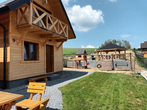 a wooden cabin with a bench and a yard at Motylowe Wzgórze Apartamenty Zawóz in Zawóz