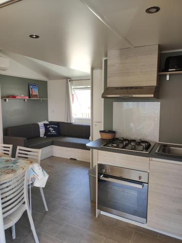 Il comprend une cuisine et un salon avec une cuisinière et une table. dans l'établissement Mobil Home Camping Mar Estang 4*, à Canet