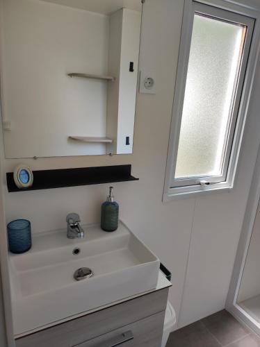 une salle de bain avec un lavabo blanc et un miroir dans l'établissement Mobil Home Camping Mar Estang 4*, à Canet
