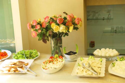 a table with a vase of flowers and bowls of food at Royal Garden Hotel in Beirut